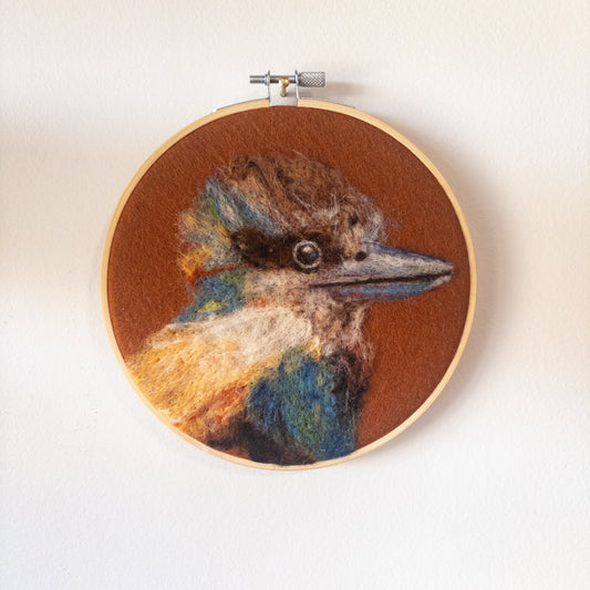 Embroidery hoop with detailed needle felting of a bird's head on a white background