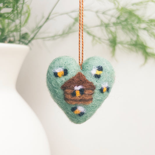 Heart-shaped felt ornament with birds and a nest, hanging against a white background.